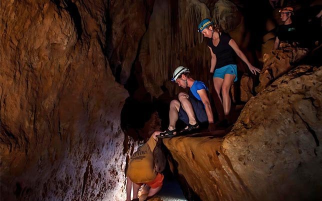 Tourists exploring the depths of Belize’s ATM Cave with helmets and headlamps with Epic Belize Adventure